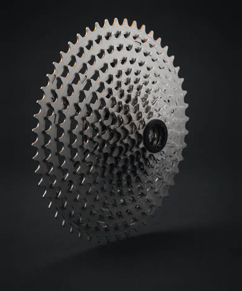 A silver bike cassette standing on its edge in low studio light