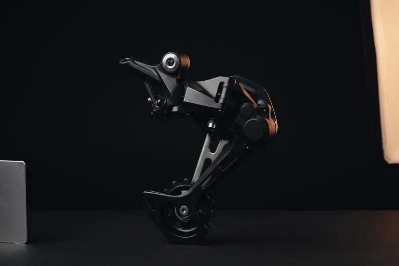 A rear derailleur on a dark studio backdrop, lit by a large softbox