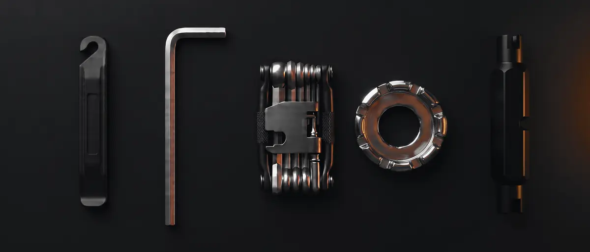 Five bike tools in a row: a tire lever, a hex key, a folding multi-tool, a spoke wrench and a valve tool