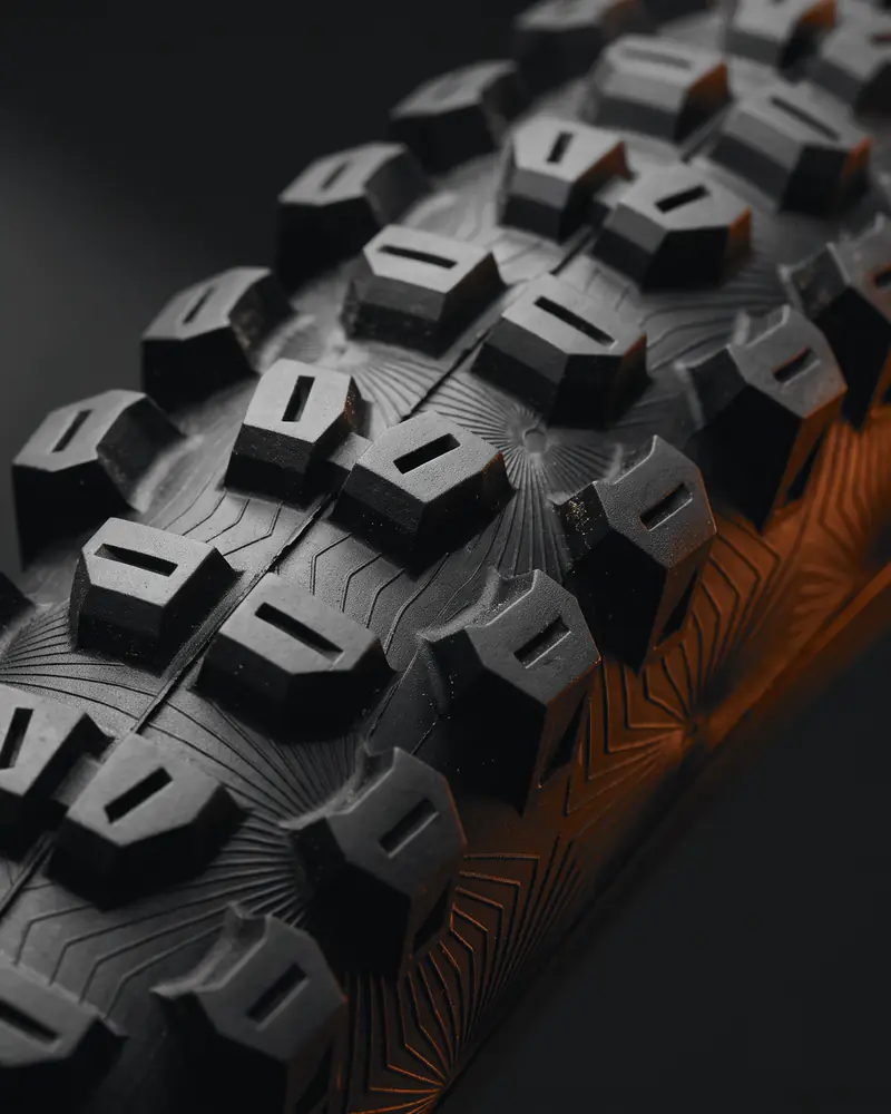 Close-up of a knobby mountain-bike tire tread in low, warm light