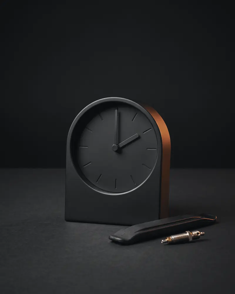 A desk clock without numbers showing two o'clock, beside a tire lever and a valve core